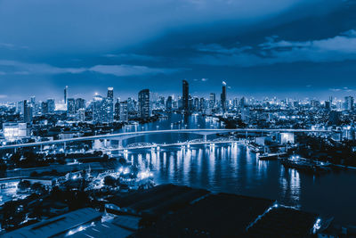 Illuminated buildings in city against sky at dusk