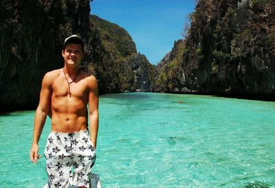 Portrait of shirtless young man standing in sea