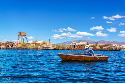 Woman rowing boat in lake titicaca against sky