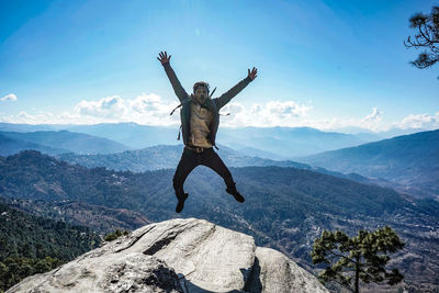 Man jumping on mountain against sky