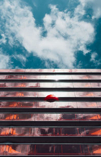 Low angle view of red building against cloudy sky