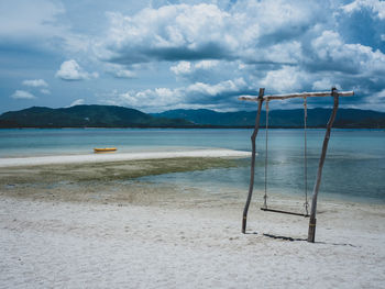 Swing and kayak on white sand beach of island, mountain and cloudy background. koh mat sum, thailand