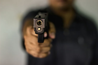 Close-up of man aiming gun against blurred background