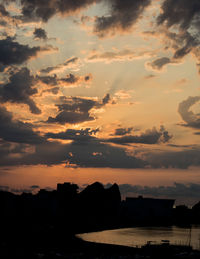 Silhouette of buildings against cloudy sky