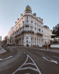 Road by buildings against clear sky