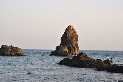 Rock formations on shore against clear sky