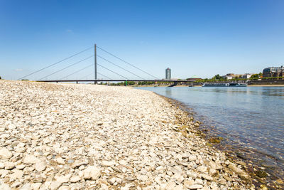 View of suspension bridge over river against clear sky