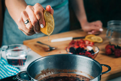 Fruit canning preservation. woman cooking fruits and making homemade jam. squeezing lemon.