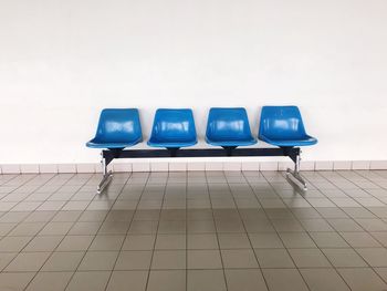 Empty chairs against tiled wall