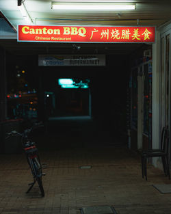 Illuminated text on footpath by building at night