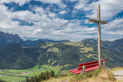 Cross on countryside landscape against clouds