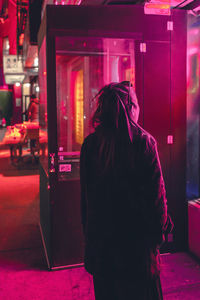 Rear view of woman standing in illuminated city at night