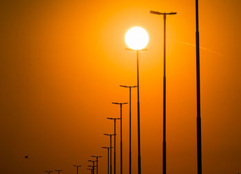 Silhouette street lights against orange sky