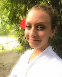 Portrait of smiling young woman against trees