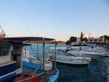 Boats moored at harbor against clear blue sky