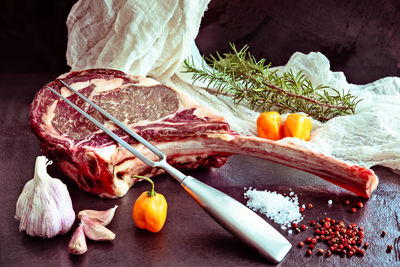 Raw ,dry-aged wagyu tomahawk steak with rosemary, salt, pepper, garlic, habanero pepper 