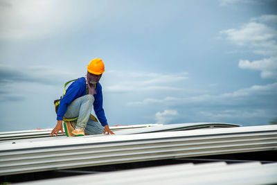 Asian construction workers are installing metal roofing sheets for industrial roof installations.