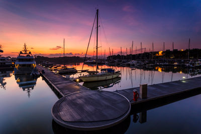 Boats moored at harbor during sunset