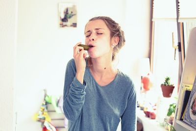 Young woman eating pickled cucumber at home