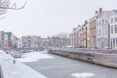 Canal amidst buildings against sky during winter