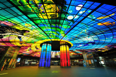 Multi colored illuminated built structure against blue sky