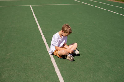 The boy is sitting on the lawn . plays on the phone