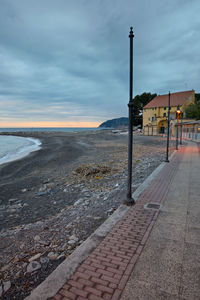 Street by sea against sky during sunset