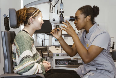 Female ophthalmologist examining patient's eye in clinic at hospital
