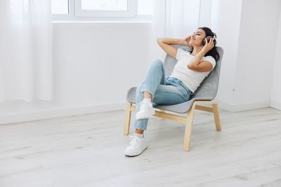 Full length of young woman sitting on sofa at home