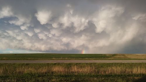 Scenic view of field against sky, rainbow