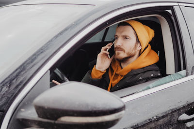 Millennial man drive the car and calling by smartphone. high quality photo