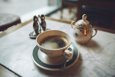 High angle view of tea cup with teapot on table