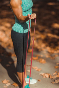 Low section of female athlete exercising with resistance band at park