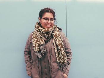 Portrait of smiling young woman standing against gray background