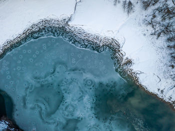 Close-up of snow covered field with frozen lake during winter