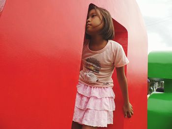 Young woman standing against red wall