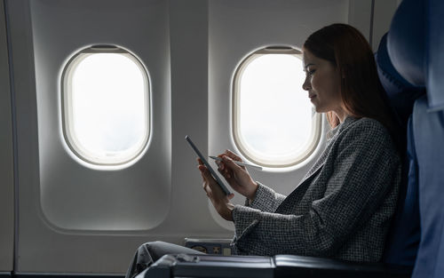 Businesswoman using tablet pc sitting in airplane