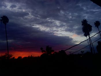 Low angle view of power lines against cloudy sky