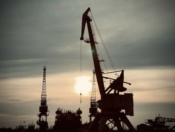 Low angle view of silhouette crane against sky during sunset
