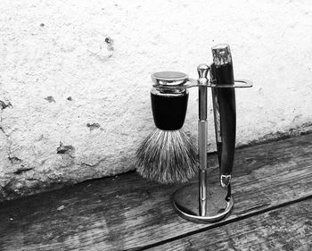 Shaving brush and old-fashioned razor on stand against wall