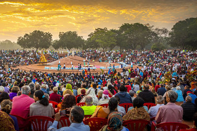 Group of people at music concert against sky during sunset