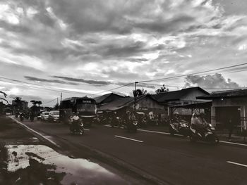 Cars on street by buildings in city against sky