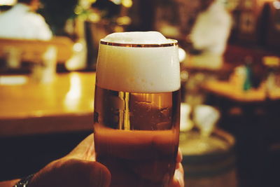 Cropped hand having beer in glass at bar