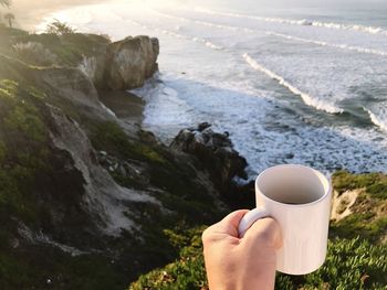 Midsection of woman holding water at beach