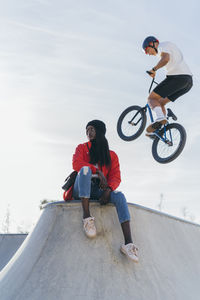 Young man riding bicycle on road against sky