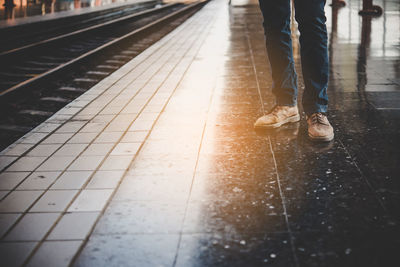 Low section of man standing at railroad station platform