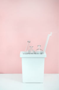 White bucket for sorting recyclables for glass on a pink background with emty space for text