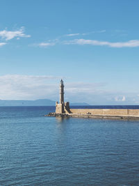 Lighthouse by sea against sky