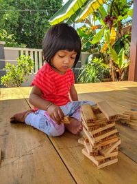 Full length of girl playing with wooden blocks at porch