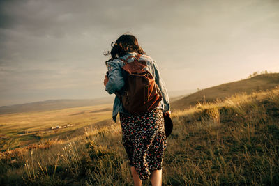 Full length of woman standing on field against sky during sunset